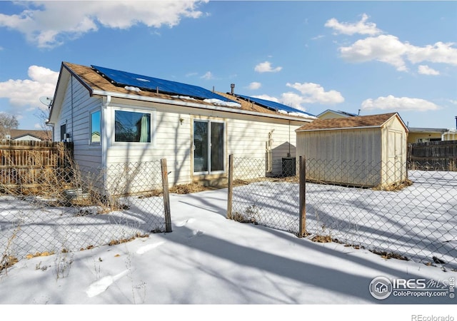 snow covered back of property with a storage shed