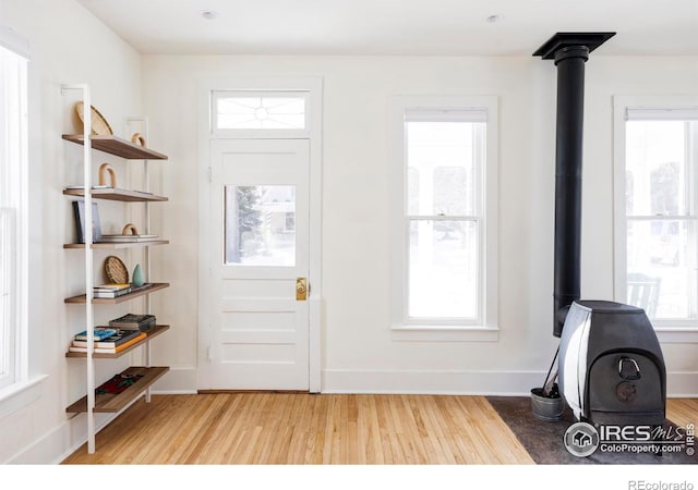 foyer with a wood stove and light hardwood / wood-style floors