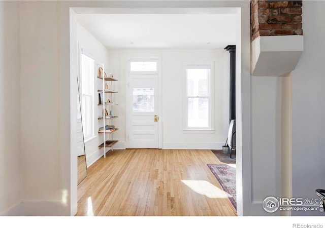 foyer entrance with wood-type flooring and a wood stove