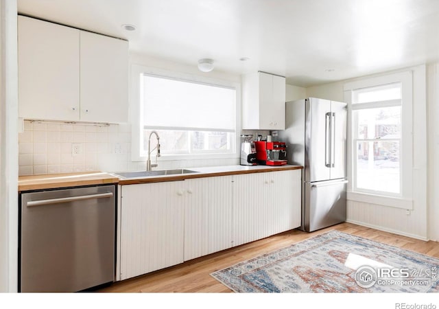 kitchen featuring stainless steel appliances, white cabinetry, sink, and a healthy amount of sunlight