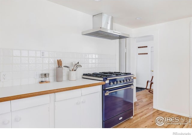 kitchen featuring tasteful backsplash, island exhaust hood, gas range oven, light hardwood / wood-style floors, and white cabinets