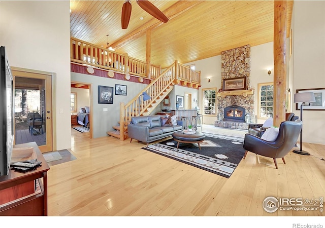 living room with wood-type flooring, a stone fireplace, high vaulted ceiling, and wood ceiling