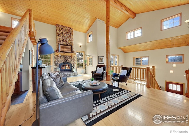 living room featuring a fireplace, high vaulted ceiling, light hardwood / wood-style flooring, and wooden ceiling