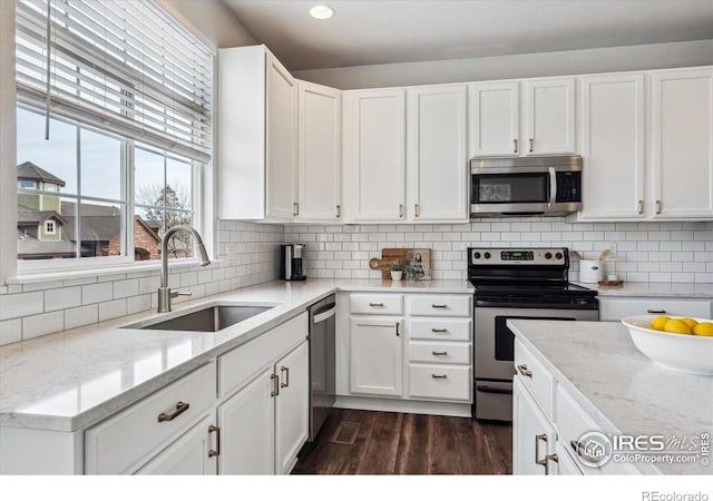 kitchen with white cabinetry, sink, light stone counters, and appliances with stainless steel finishes