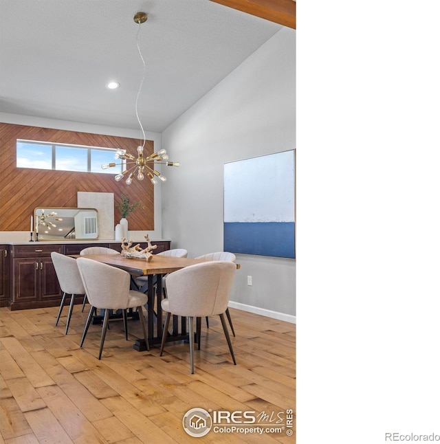 dining space featuring lofted ceiling, light hardwood / wood-style flooring, and a chandelier