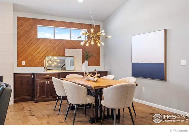 dining space with light hardwood / wood-style floors and a notable chandelier