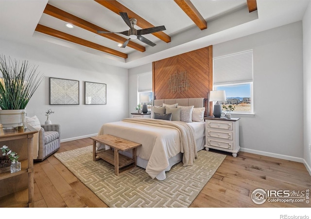 bedroom featuring ceiling fan, a tray ceiling, light hardwood / wood-style flooring, and beamed ceiling