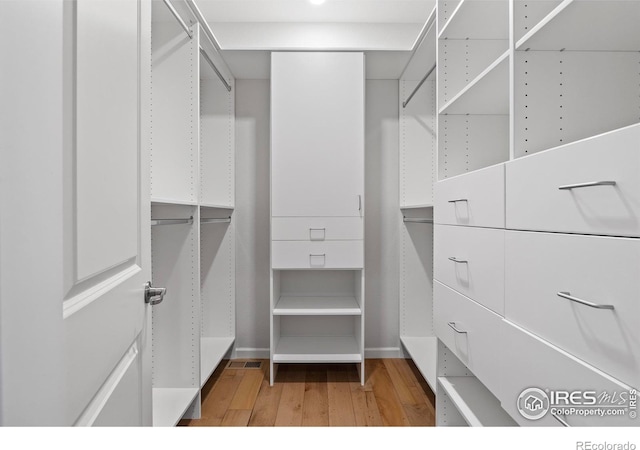 walk in closet with light hardwood / wood-style floors