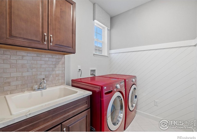 washroom with cabinets, washing machine and dryer, and sink