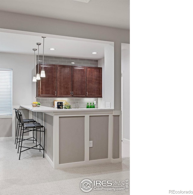 kitchen with tasteful backsplash, kitchen peninsula, a kitchen breakfast bar, and decorative light fixtures