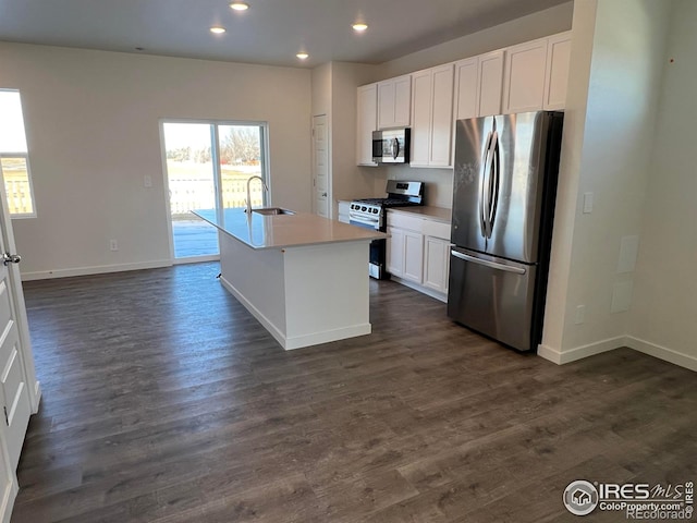 kitchen featuring stainless steel appliances, white cabinetry, sink, and a center island with sink