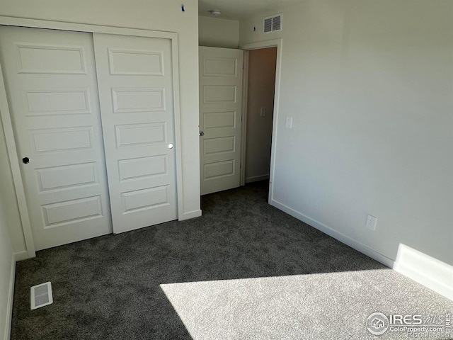 unfurnished bedroom with dark carpet and a closet