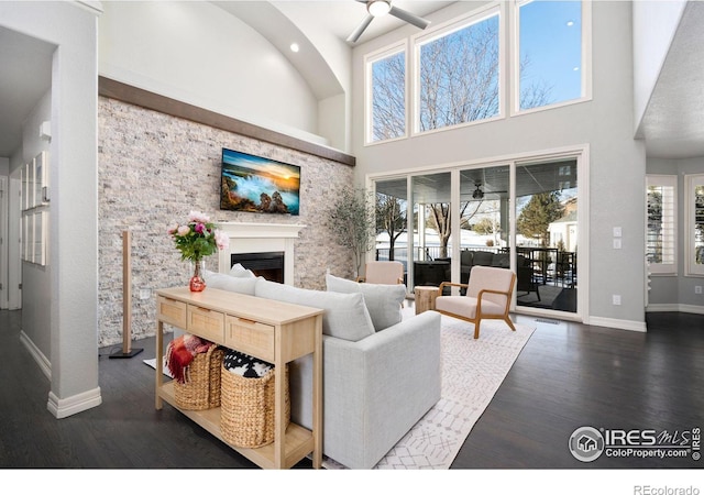 living room with dark hardwood / wood-style floors, ceiling fan, and a towering ceiling