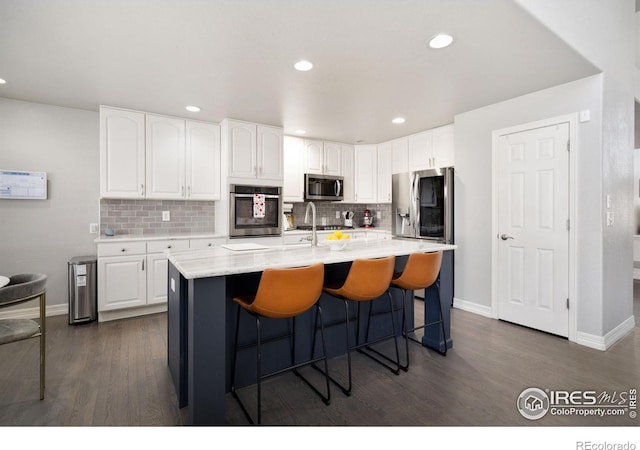 kitchen featuring stainless steel appliances, a center island with sink, and white cabinets