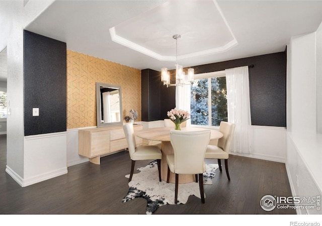 dining space with an inviting chandelier, a tray ceiling, and dark hardwood / wood-style flooring