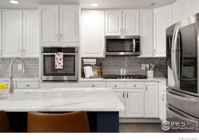 kitchen with white cabinetry, backsplash, dark hardwood / wood-style flooring, and stainless steel appliances