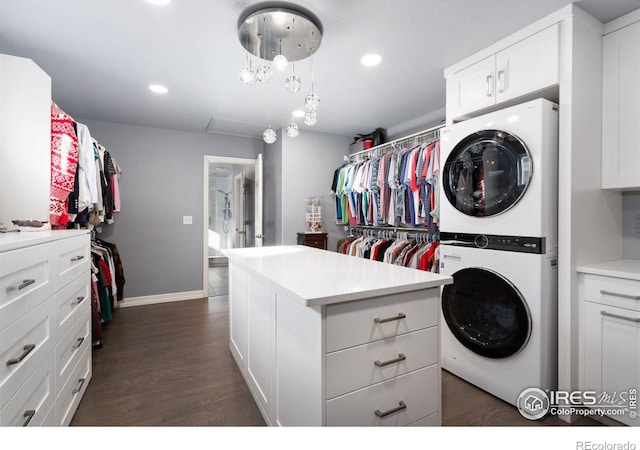 spacious closet featuring stacked washer / drying machine and dark hardwood / wood-style floors