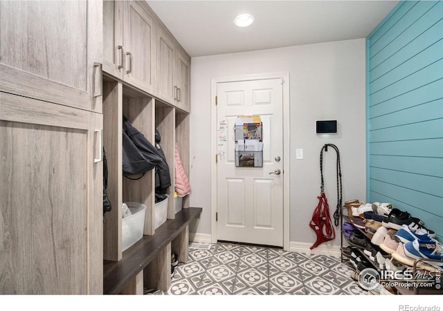 mudroom with light tile patterned flooring and wood walls