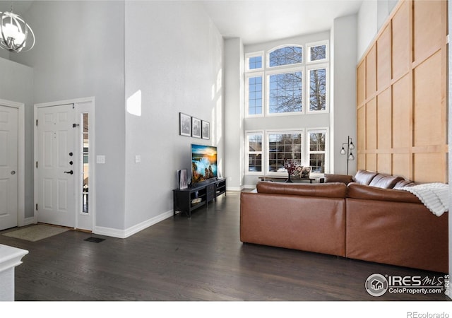 living room with an inviting chandelier, dark wood-type flooring, and a high ceiling