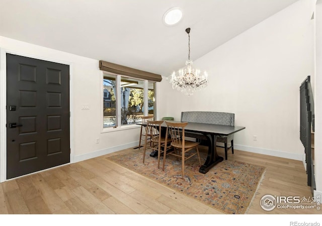 dining space featuring lofted ceiling, a notable chandelier, and light wood-type flooring