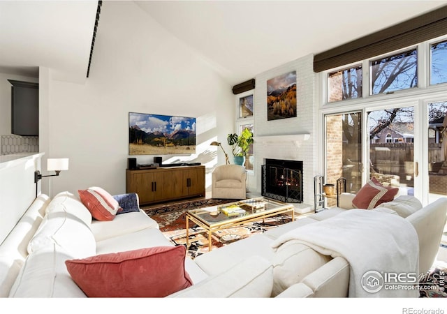 living room featuring a brick fireplace and high vaulted ceiling