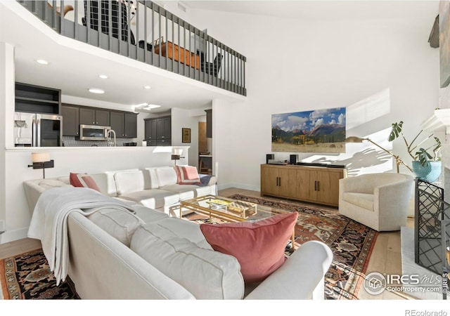 living room with wood-type flooring, sink, and a high ceiling