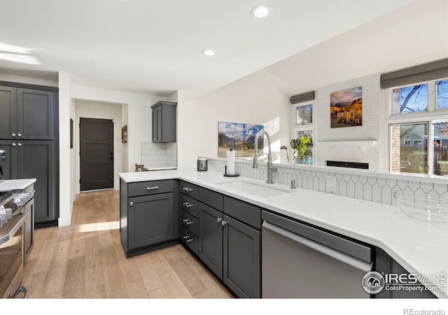 kitchen with gray cabinetry, sink, kitchen peninsula, and dishwasher