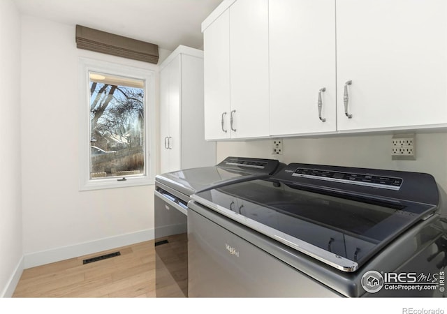 laundry area with cabinets, washer and dryer, and light wood-type flooring