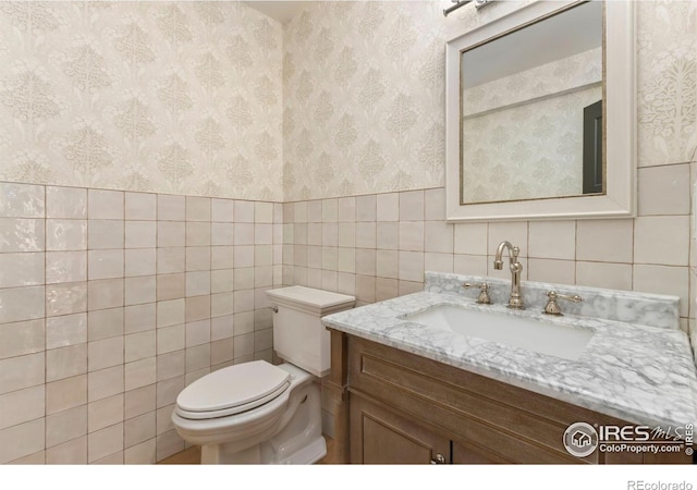 bathroom with vanity, tile walls, and toilet