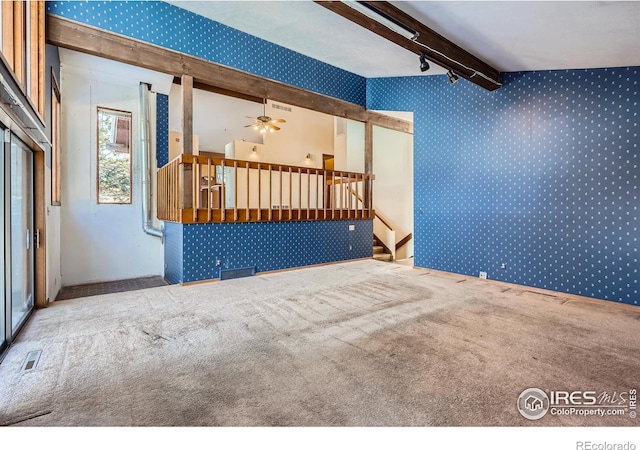 carpeted empty room featuring beam ceiling and ceiling fan