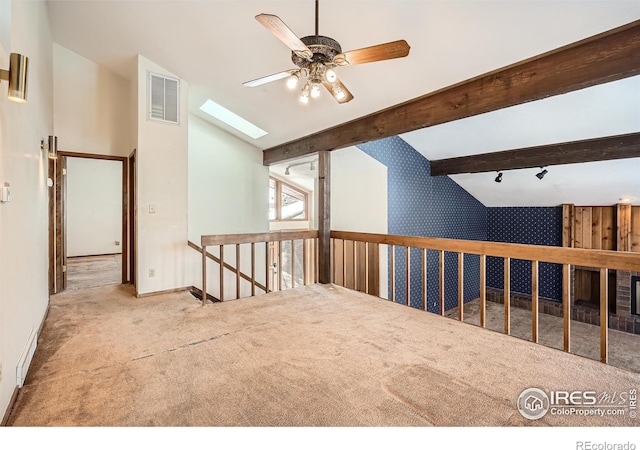 spare room featuring ceiling fan, vaulted ceiling with skylight, and light carpet