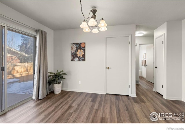 unfurnished dining area with dark hardwood / wood-style floors and an inviting chandelier