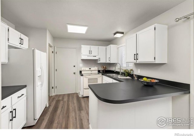 kitchen with sink, white appliances, dark wood-type flooring, white cabinets, and kitchen peninsula