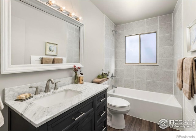 full bathroom featuring vanity, hardwood / wood-style flooring, tiled shower / bath combo, and toilet