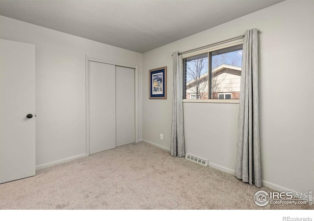 unfurnished bedroom with light carpet and a closet