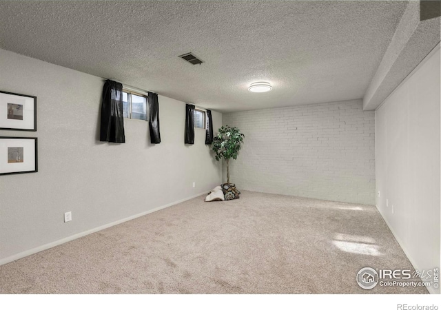 basement with brick wall, carpet, and a textured ceiling