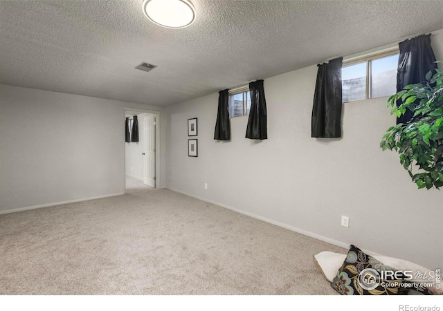 spare room with light colored carpet and a textured ceiling