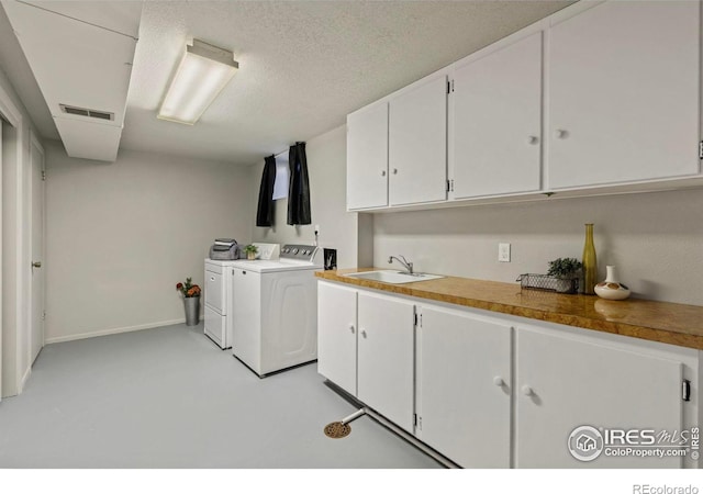 washroom with sink, washing machine and dryer, cabinets, and a textured ceiling