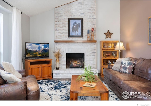 living room with lofted ceiling and a brick fireplace