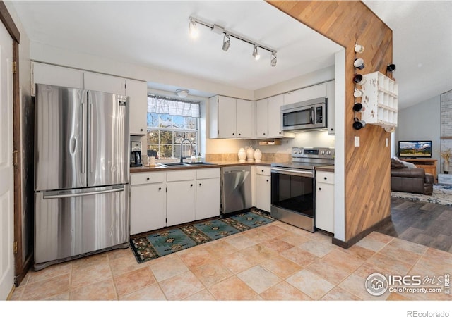 kitchen with stainless steel appliances, white cabinetry, and sink