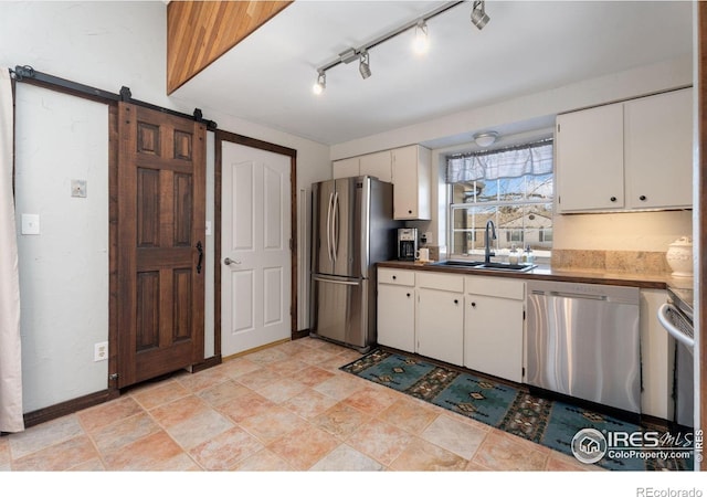 kitchen with white cabinetry, appliances with stainless steel finishes, a barn door, and sink