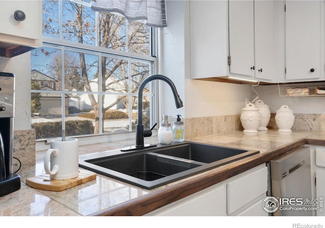 kitchen with white cabinetry, dishwasher, and sink