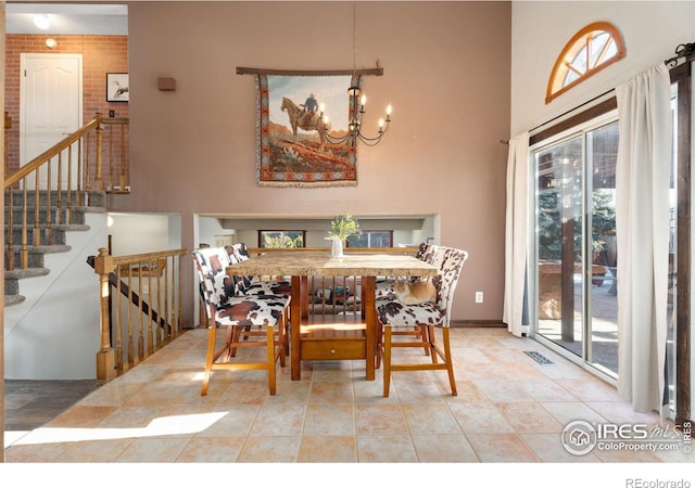 tiled dining area with an inviting chandelier and a high ceiling