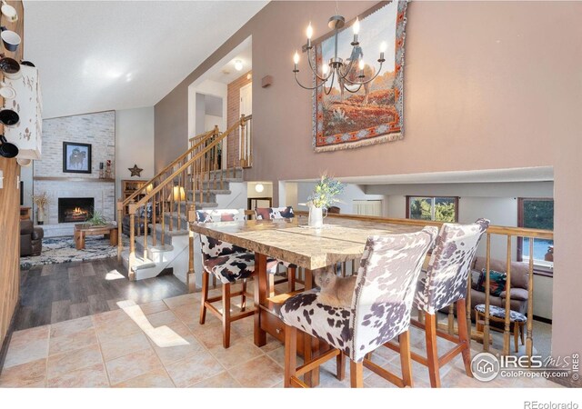 dining area with an inviting chandelier, a fireplace, and high vaulted ceiling