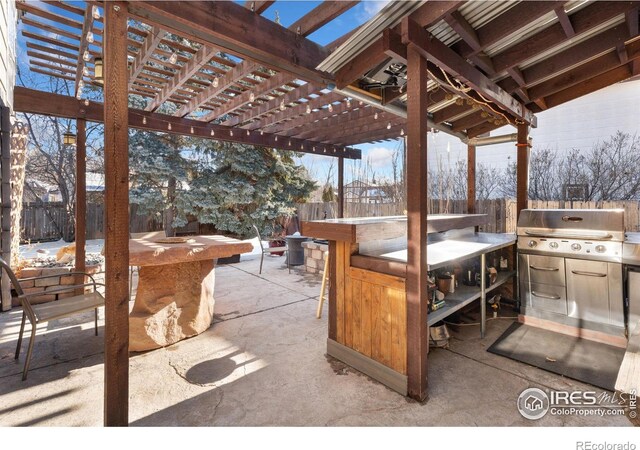 snow covered patio with exterior kitchen, a pergola, grilling area, and a bar