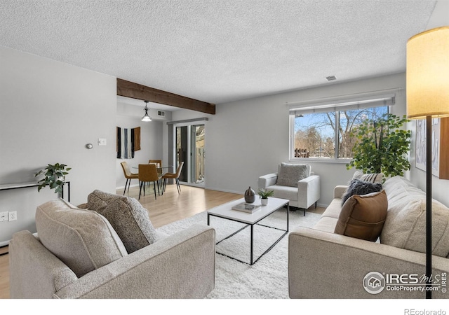 living room with beam ceiling, light hardwood / wood-style flooring, and a textured ceiling