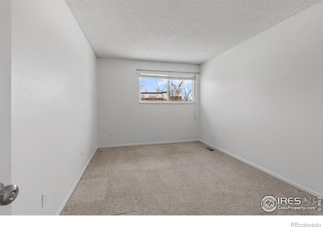 empty room featuring light colored carpet and a textured ceiling