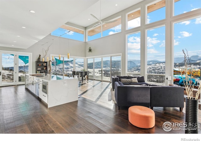 living room with a mountain view, dark wood-type flooring, and ceiling fan