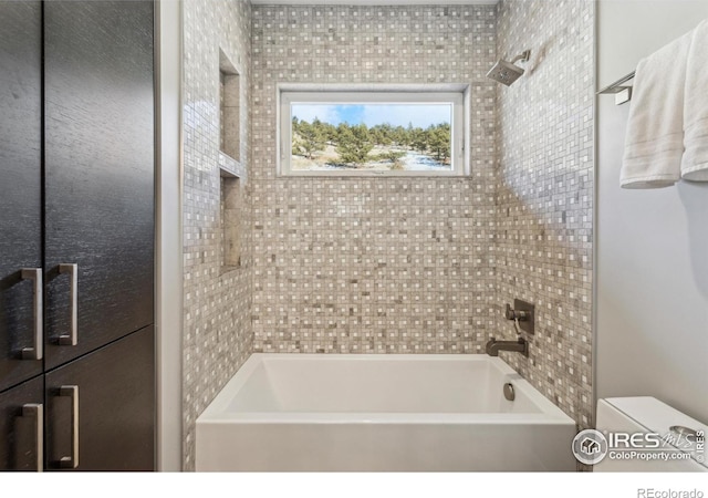 bathroom with toilet and tiled shower / bath