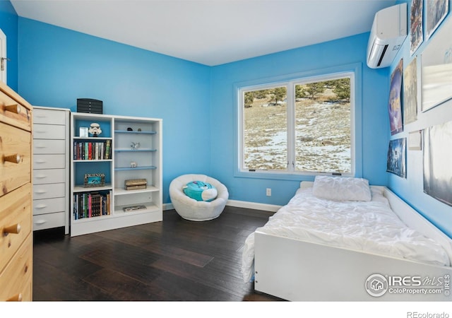 bedroom with dark hardwood / wood-style floors and a wall unit AC